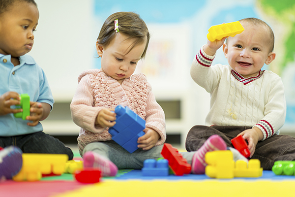 Diverse group of babies playing with large lego blocks